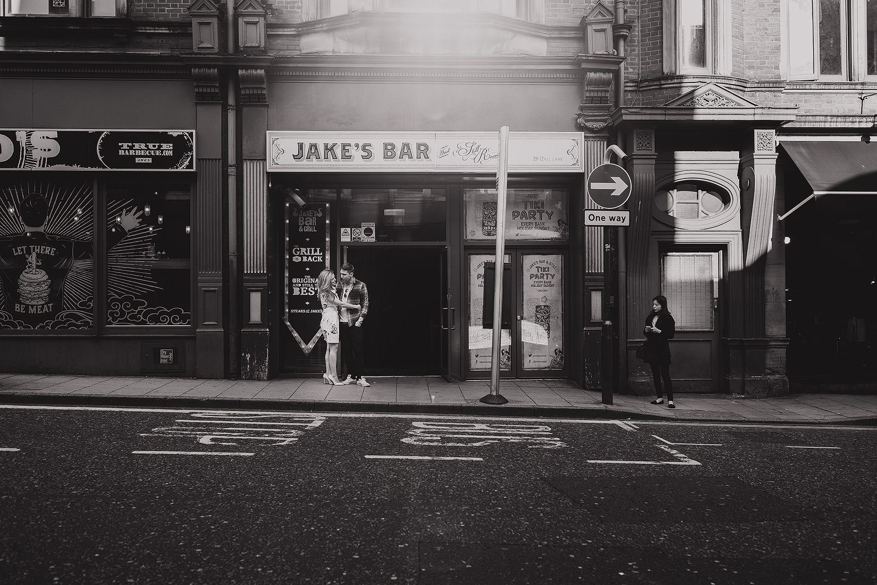 Black and white photograph of a couple stood outside Jake's Bar in Leeds