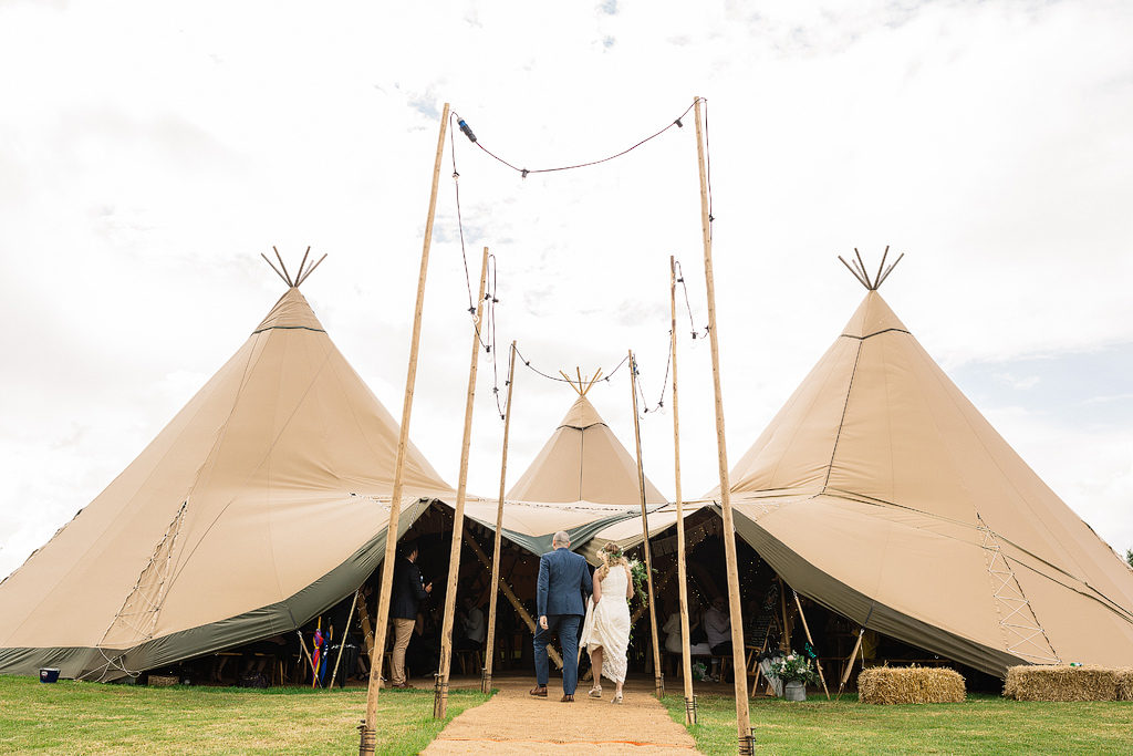 bride and groom walking into their tipi wedding