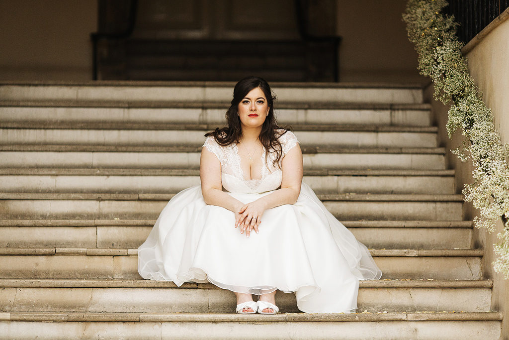 bride sitting on the steps at a castle wedding in the uk