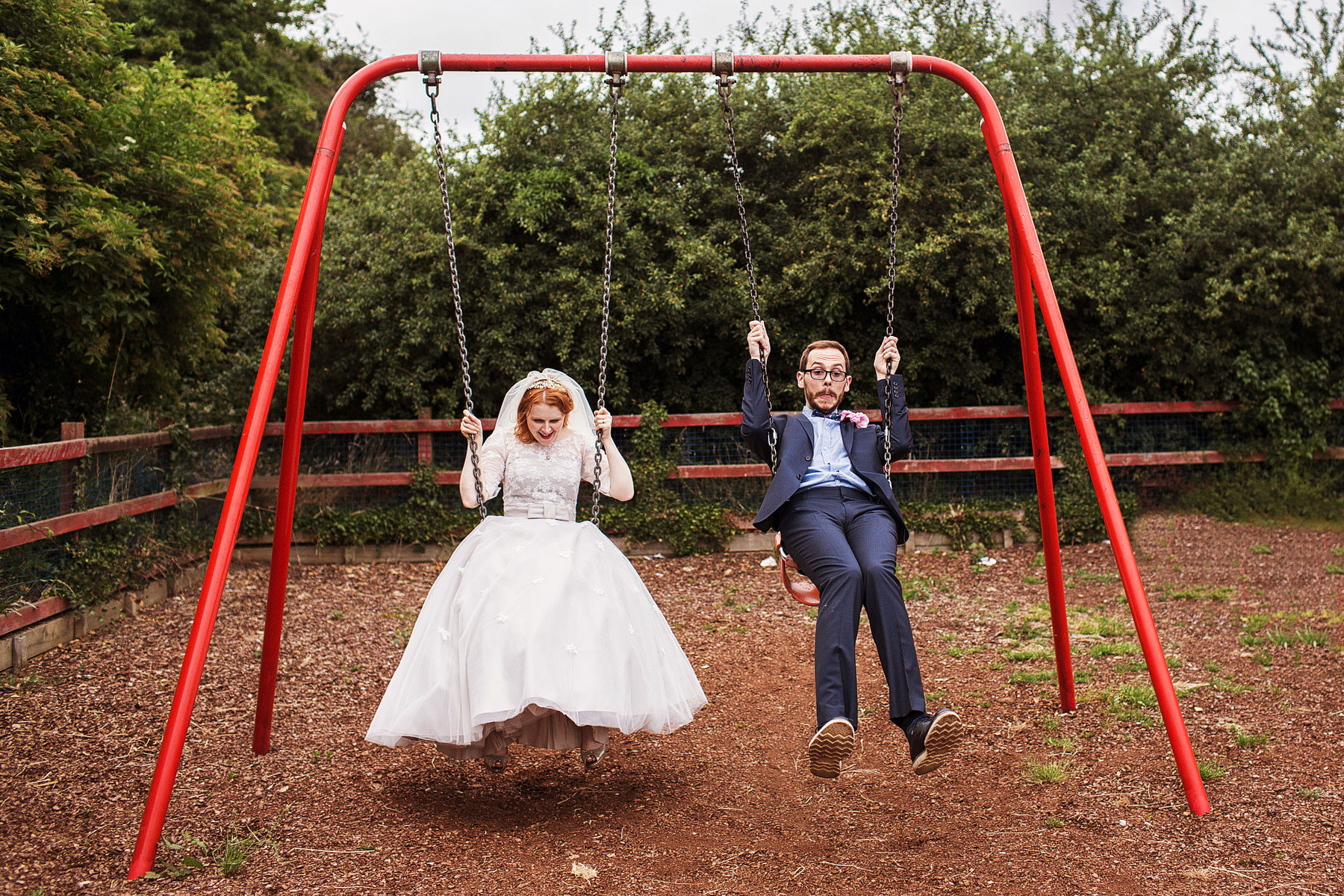 bride and groom having fun on the swings