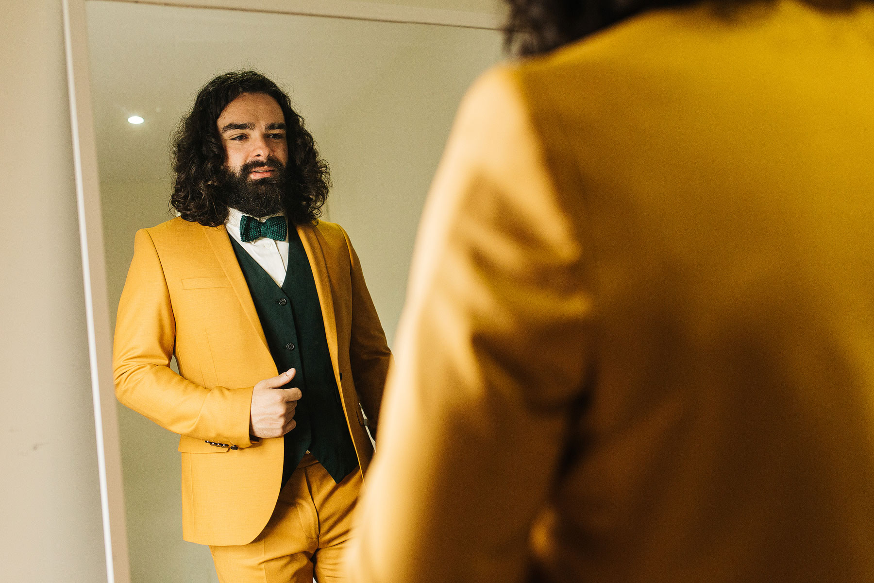 groom wearing a mustard suit with a bow tie