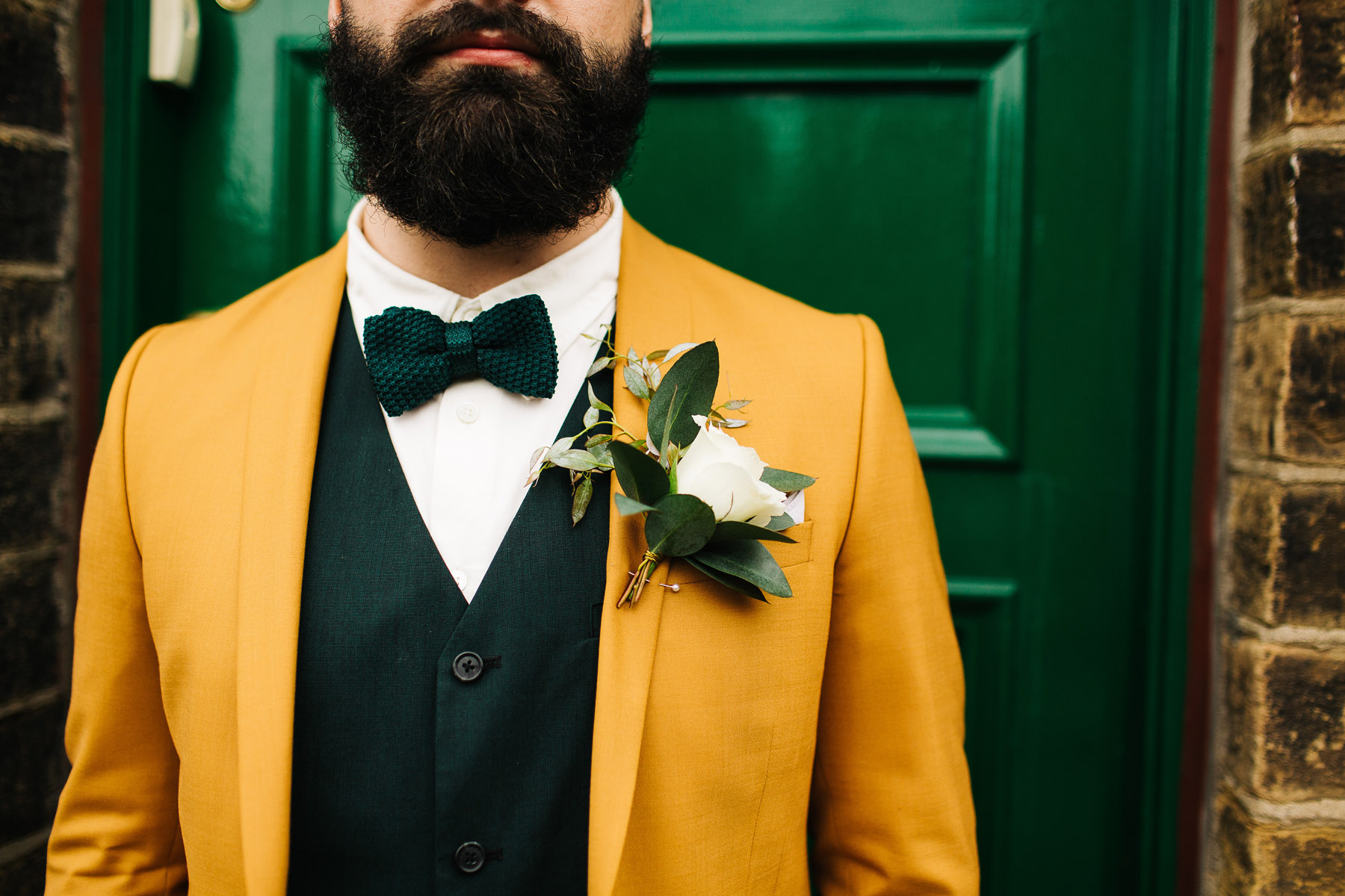Groom wearing mustard suit and a green bow tie