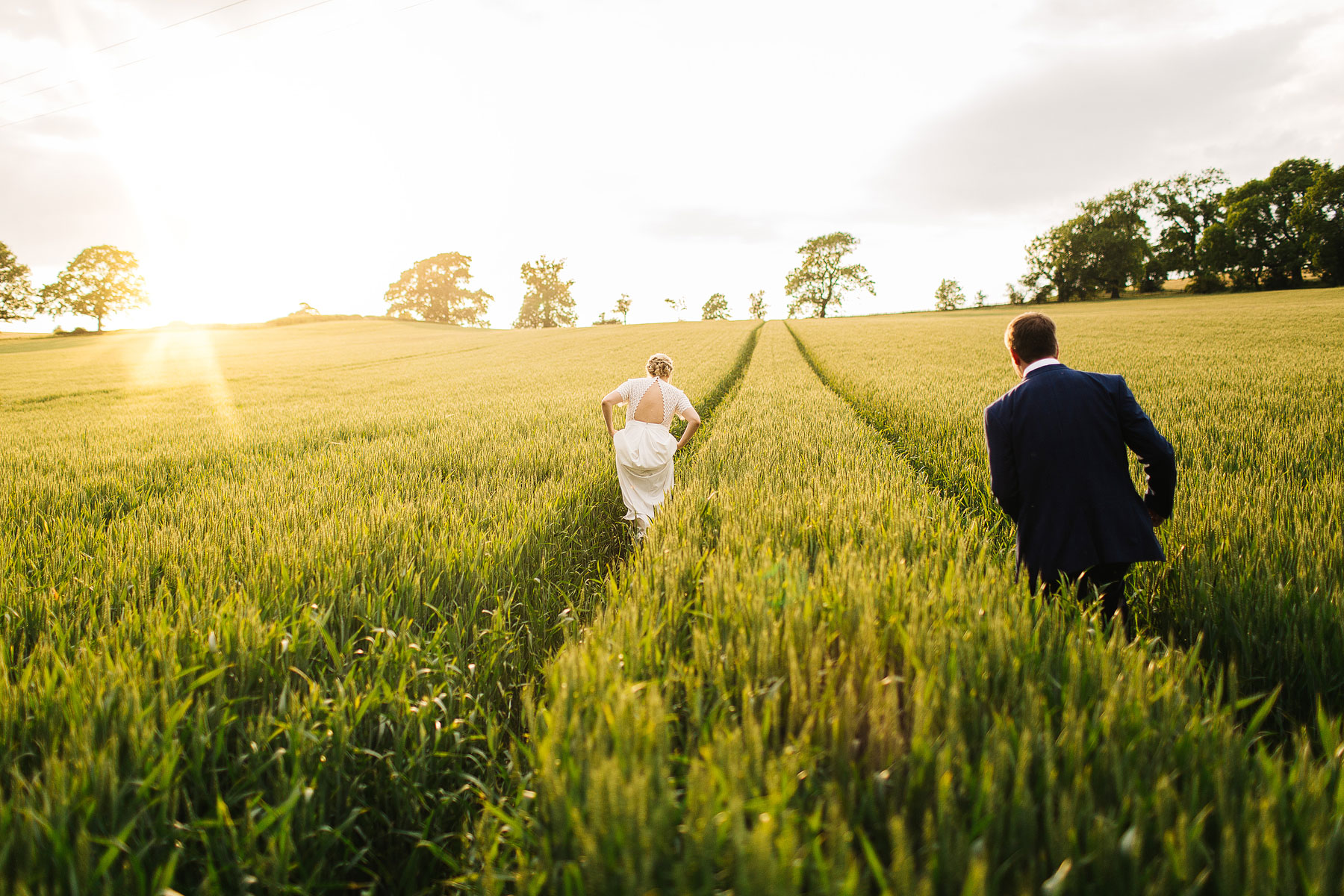 bride and groom walking through cornfields in north yorkshire