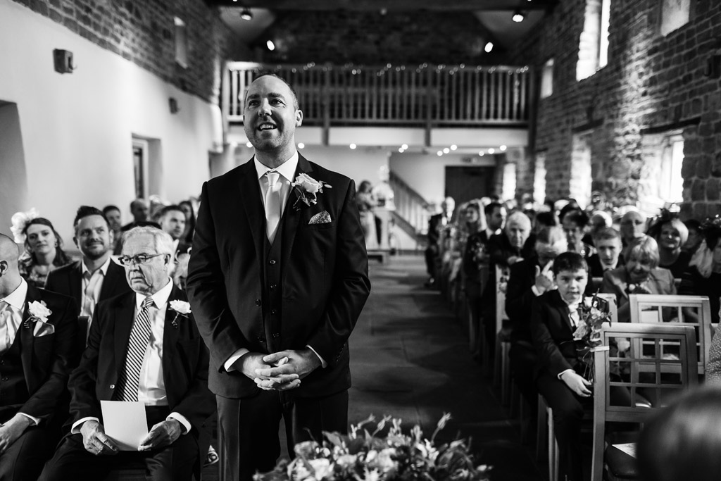 Groom waiting at the front of the aisle 