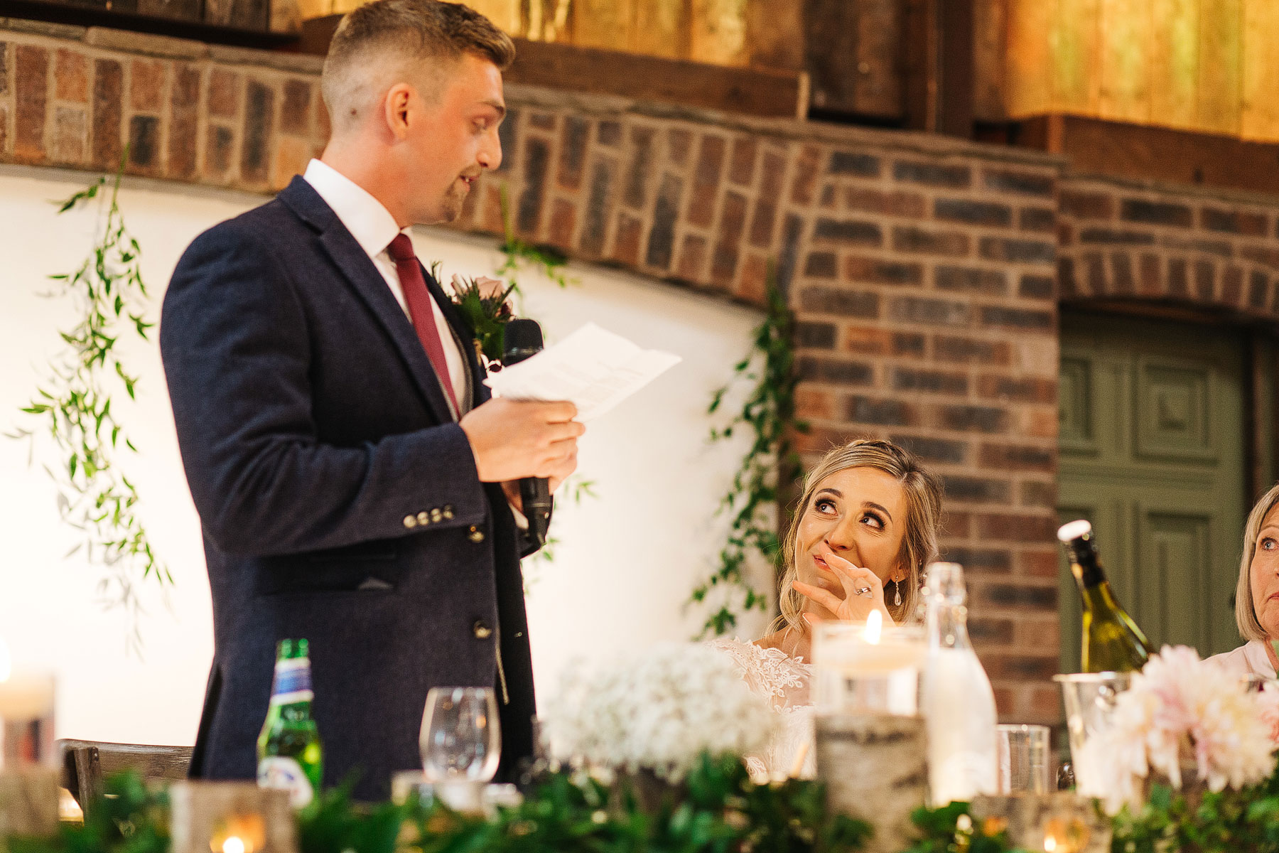 emotional bride looking at her groom making a speech