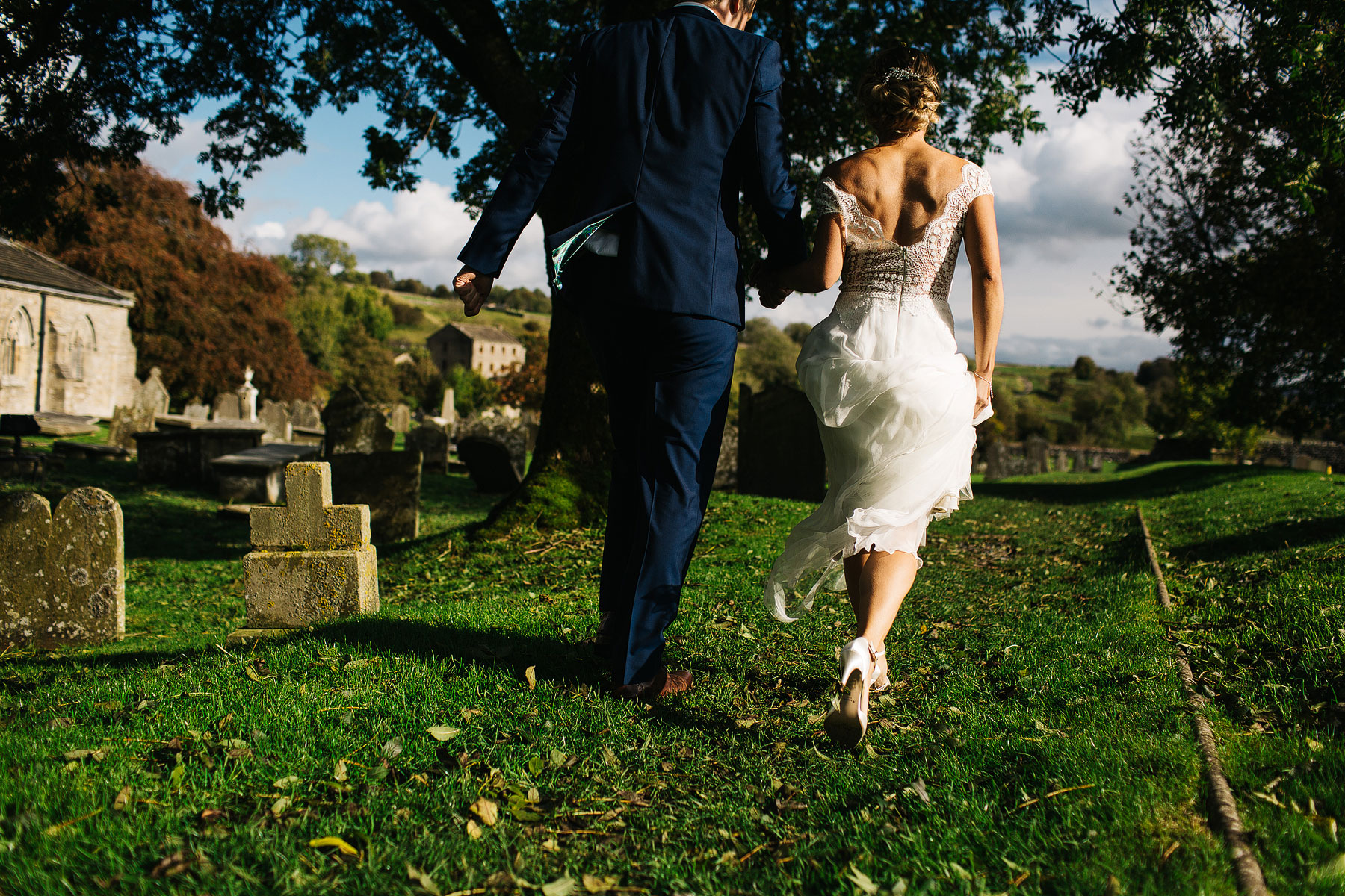 bride and groom walking through the church yard at linton falls in north yorkshire