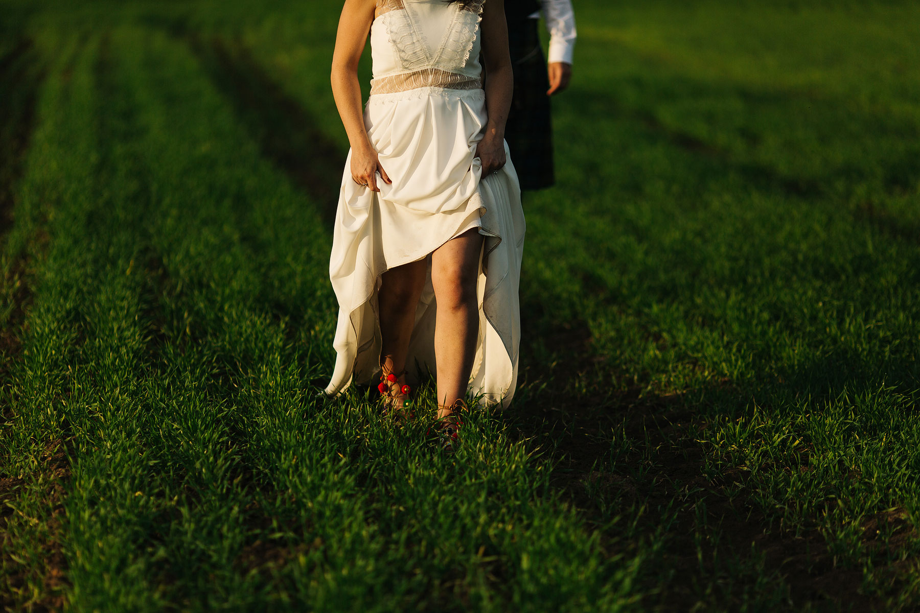 bride and groom walking through a field