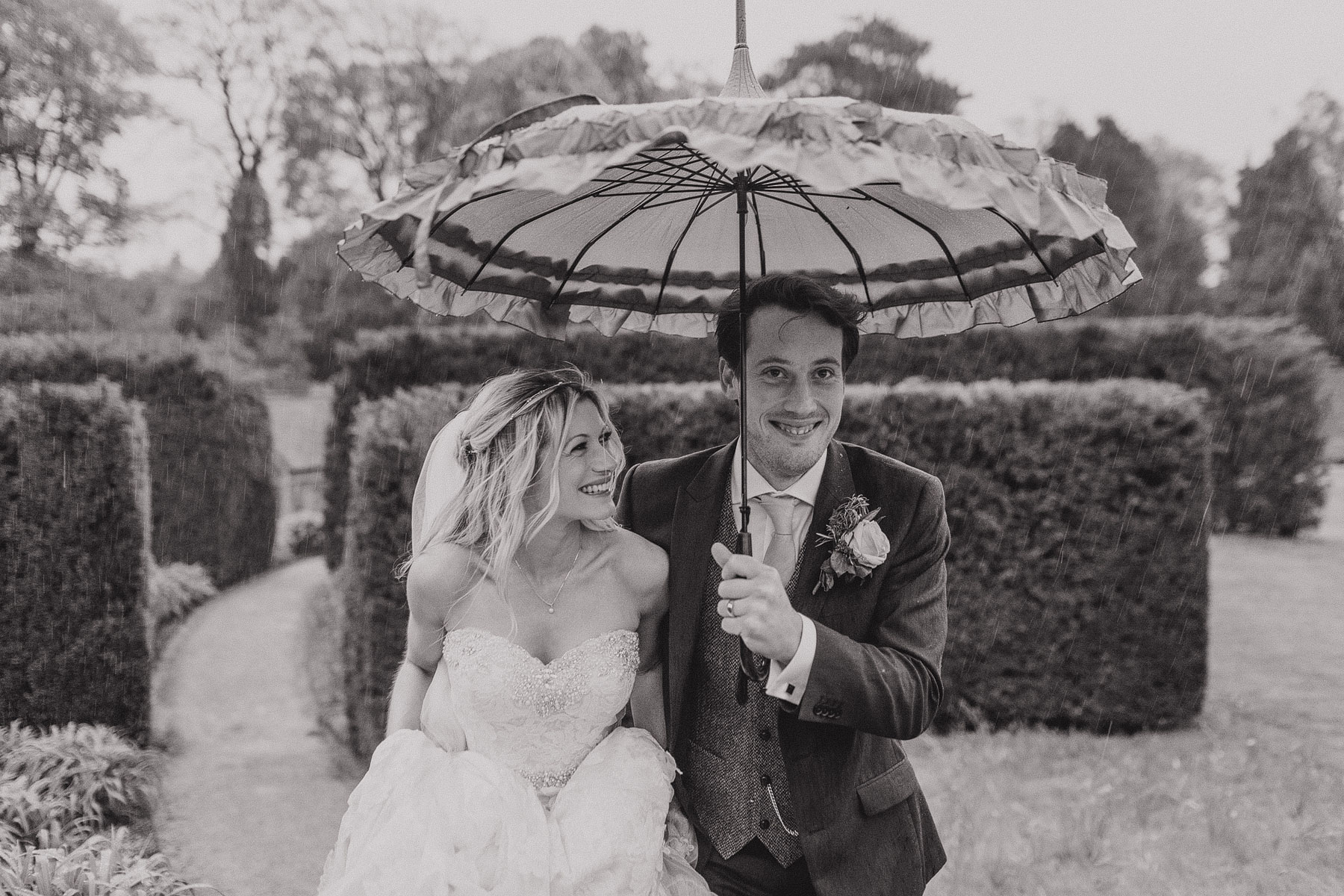 rain on your wedding day with a bride and groom holding an umbrella