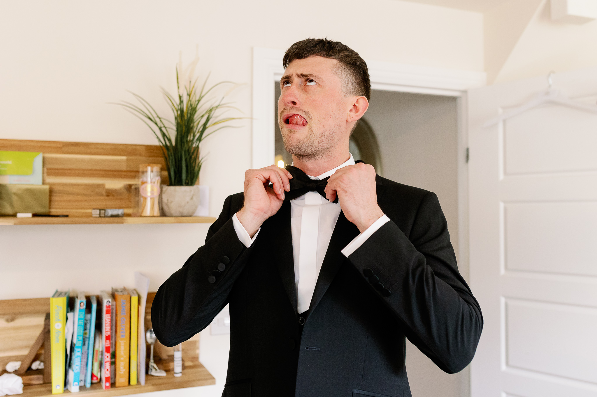 Fun Picture of a groom tying hi bow tie 