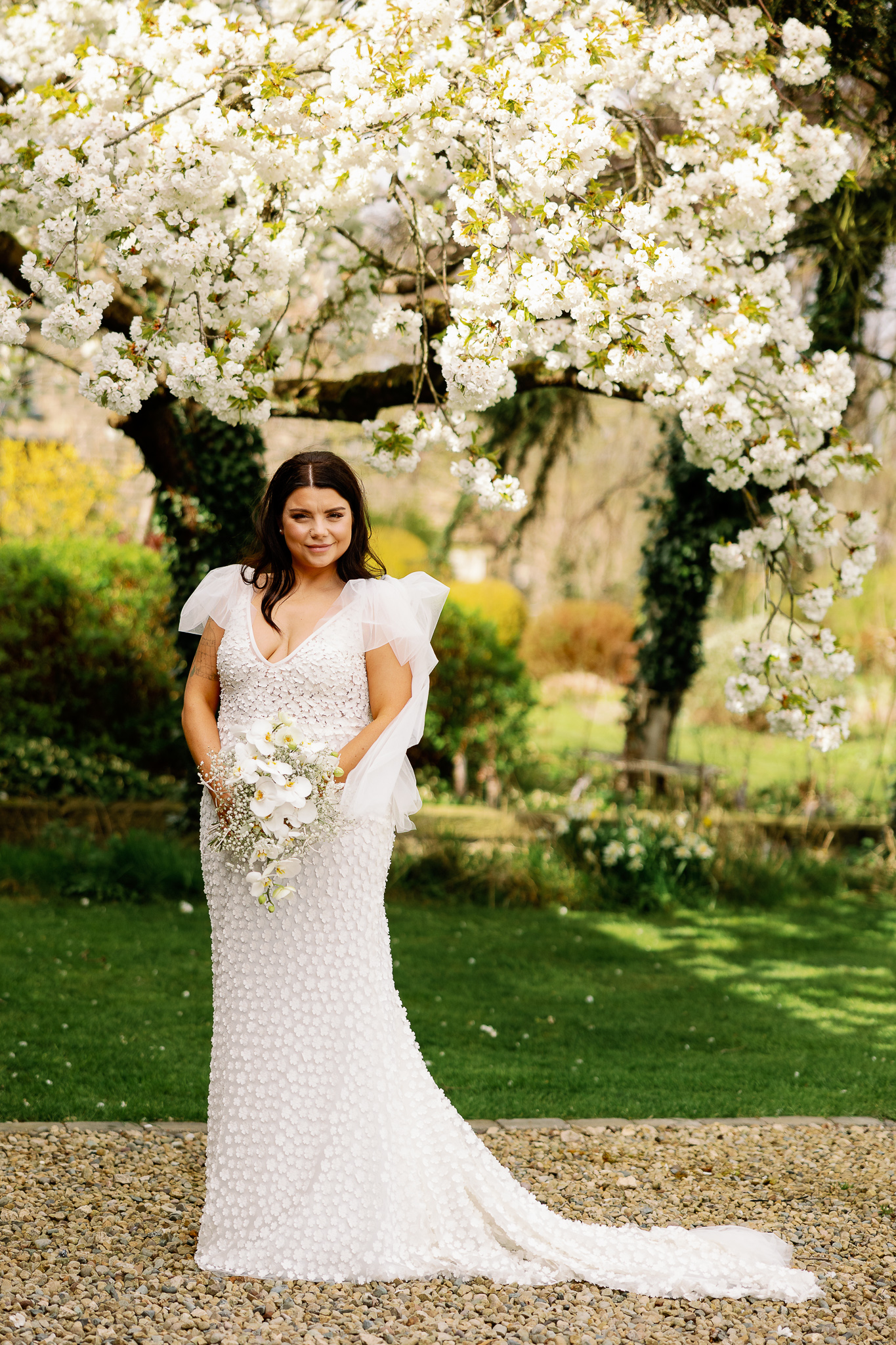 Beautiful bride holding her Yorkshire Dales Wedding Flowers by a blossom tree