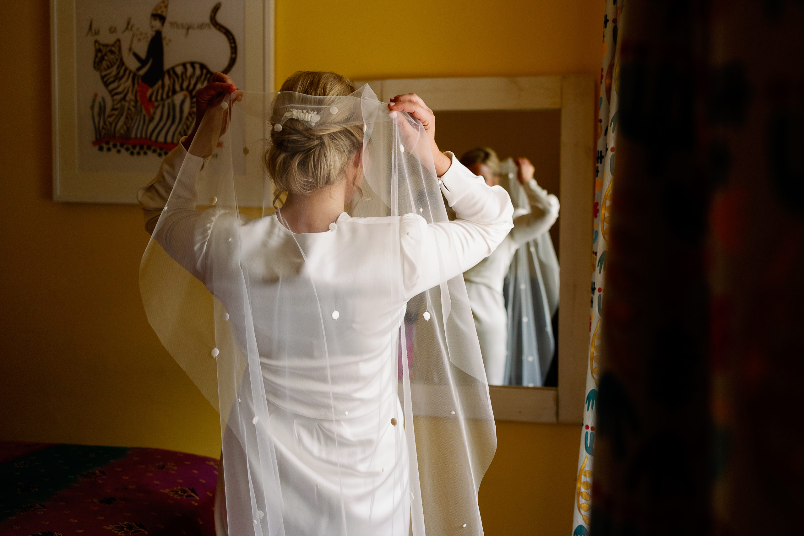 Bride putting her veil on before her wedding at Broughton Hall