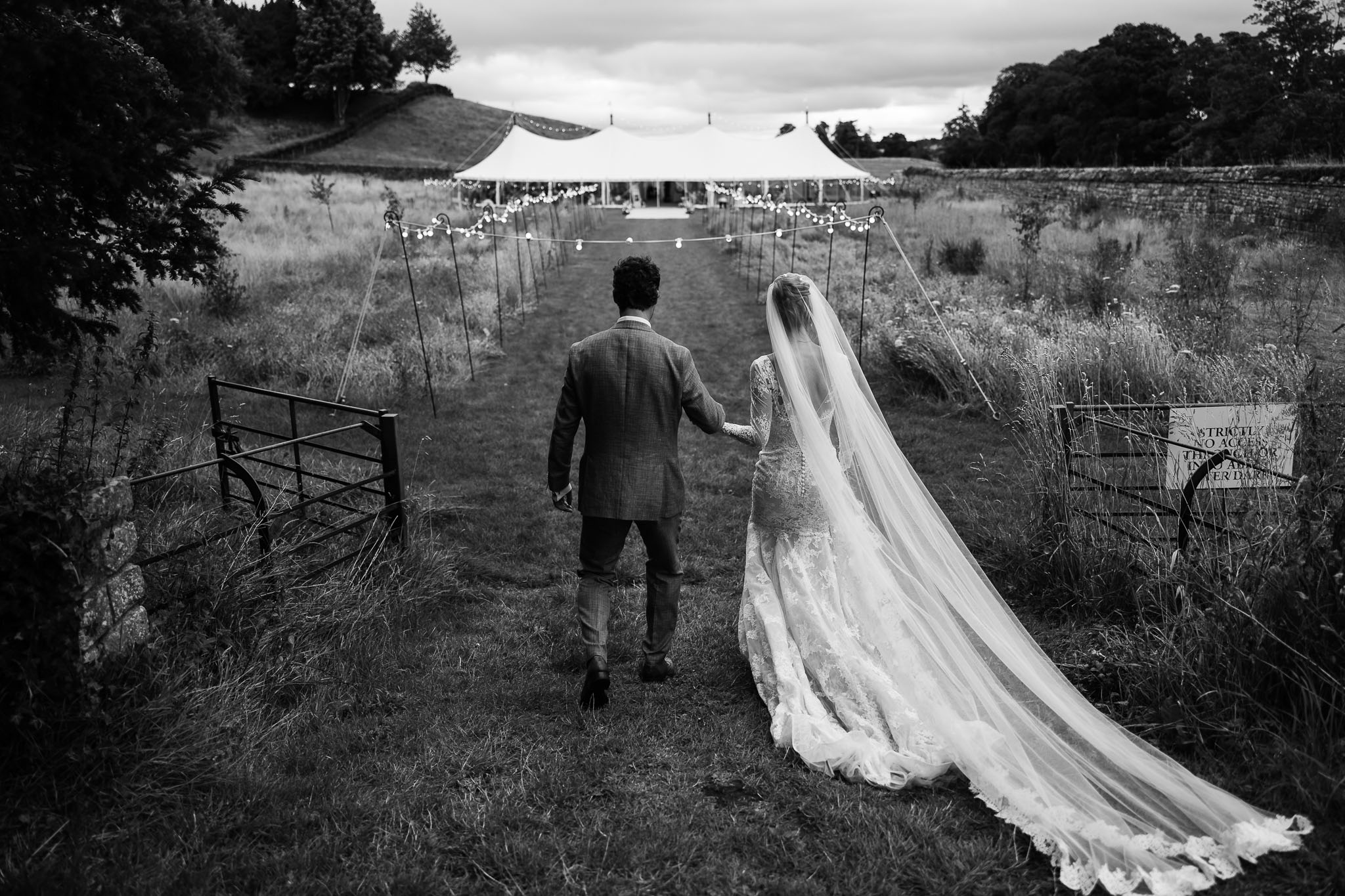 Bride and groom walking to sperry tent at Jervaulx Abbey